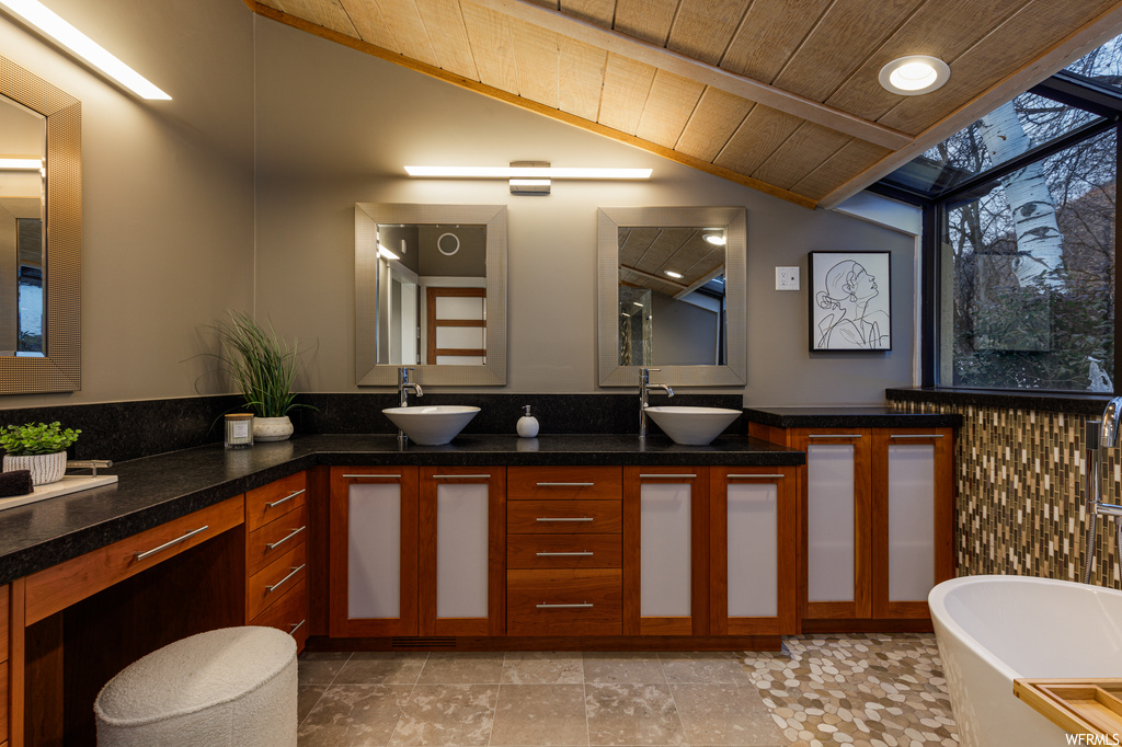 Bathroom featuring tile flooring, wood ceiling, lofted ceiling, double sink vanity, and a washtub
