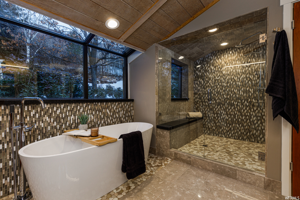 Bathroom featuring wooden ceiling, tile floors, tile walls, and shower with separate bathtub