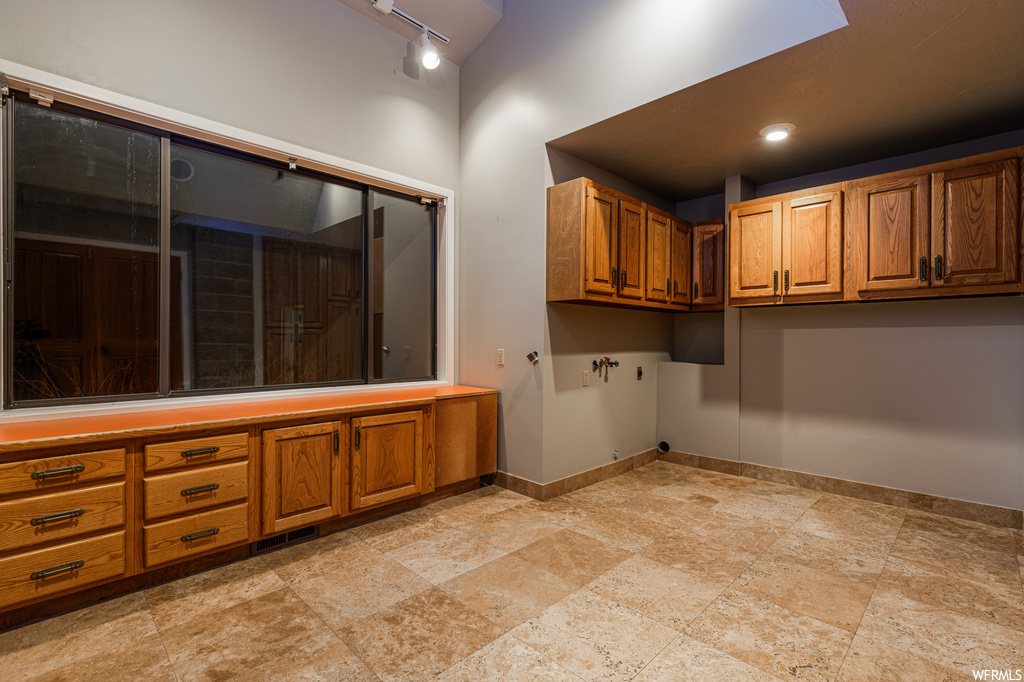 Interior space featuring cabinets, light tile flooring, and rail lighting
