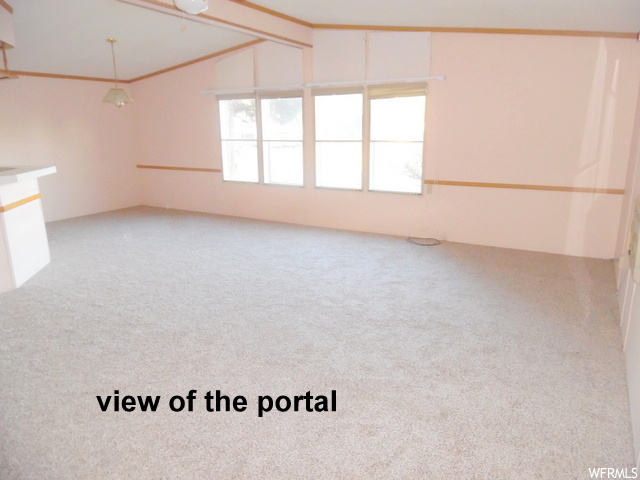 Empty room with lofted ceiling and light carpet