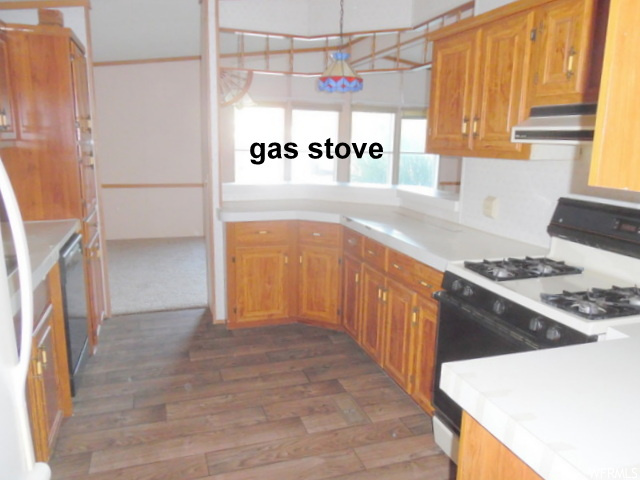 Kitchen featuring decorative light fixtures, white gas stove, dishwasher, and wood-type flooring