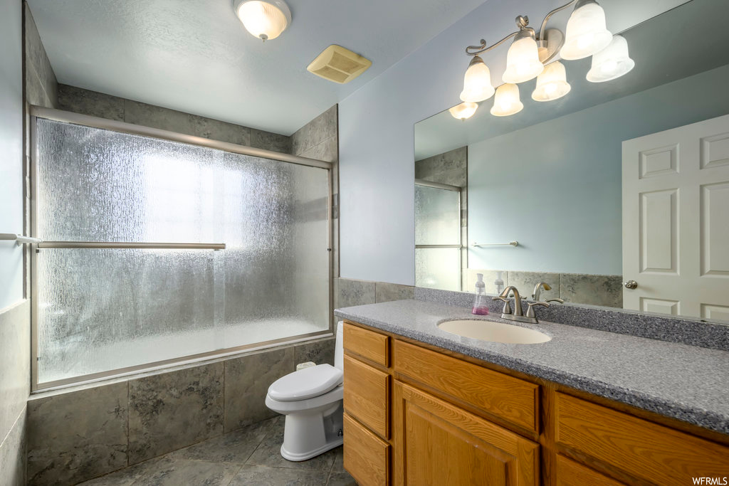 Full bathroom featuring toilet, a wealth of natural light, tile floors, and vanity with extensive cabinet space