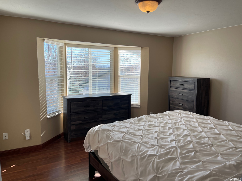 Bedroom with multiple windows and dark wood-type flooring