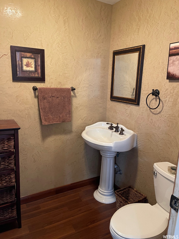 Bathroom featuring toilet, sink, and hardwood / wood-style flooring