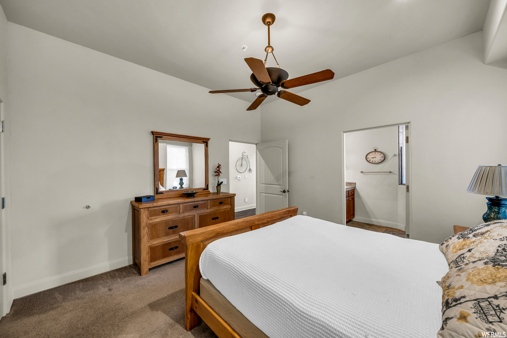 Bedroom with dark carpet, connected bathroom, and ceiling fan