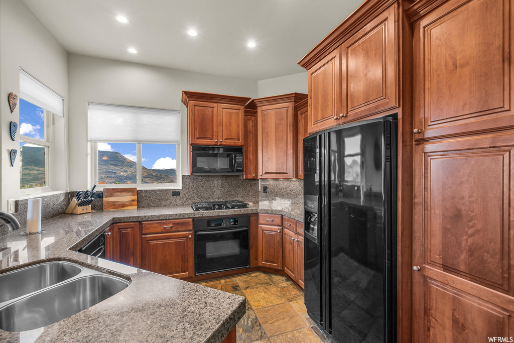 Kitchen featuring light tile floors, black appliances, sink, and tasteful backsplash