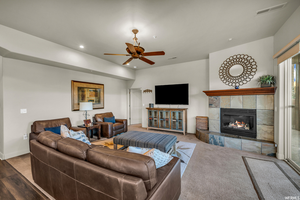 Living room with a tile fireplace, ceiling fan, and light carpet