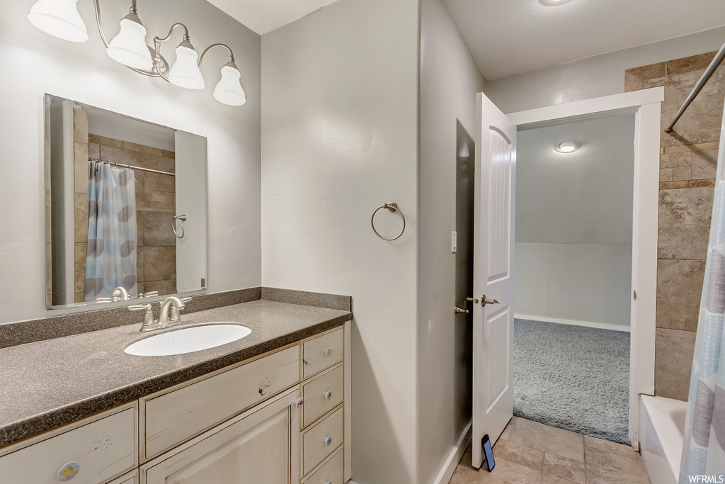 Bathroom featuring shower / bath combination with curtain, tile flooring, and vanity with extensive cabinet space