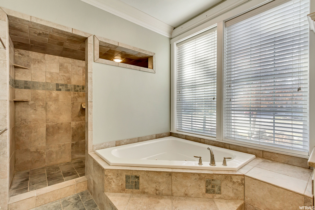 Bathroom with tile floors, tiled tub, and crown molding