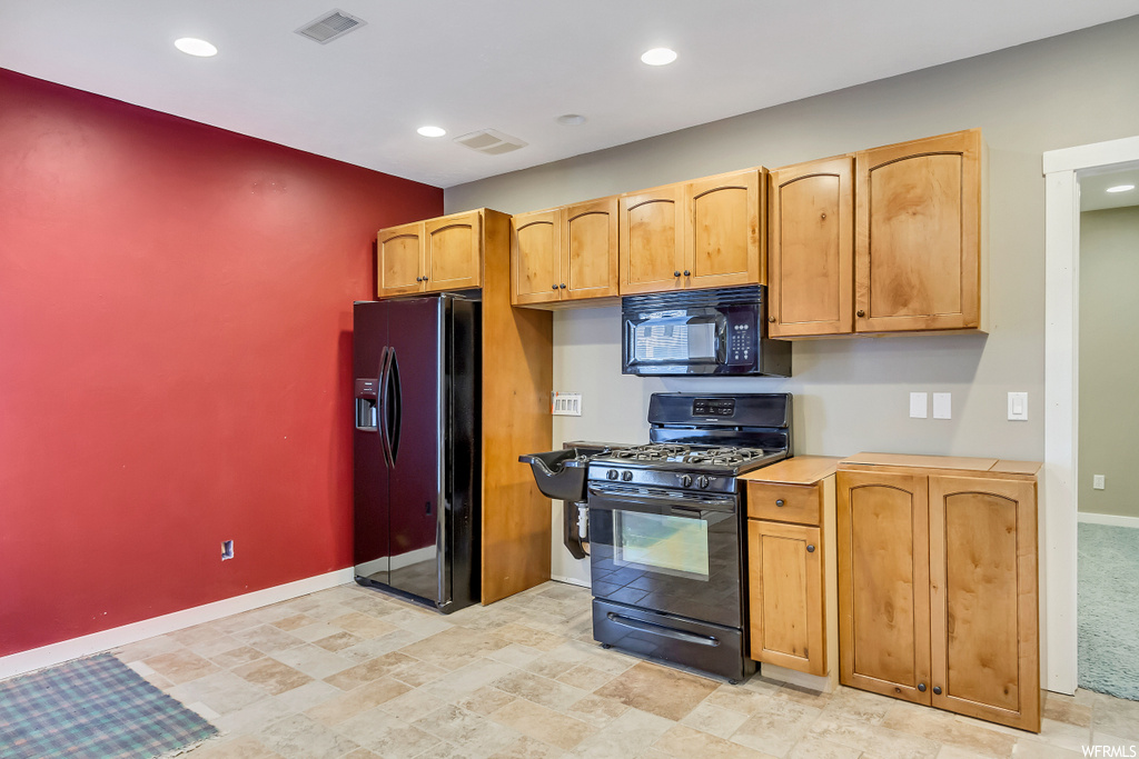 Kitchen featuring black appliances and light colored carpet