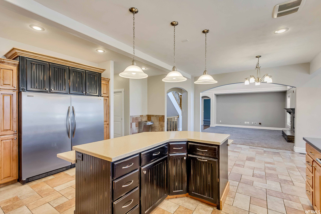 Kitchen featuring hanging light fixtures, a kitchen island, light carpet, and stainless steel fridge