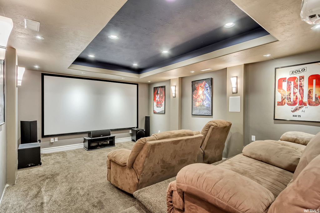 Carpeted cinema room featuring a raised ceiling