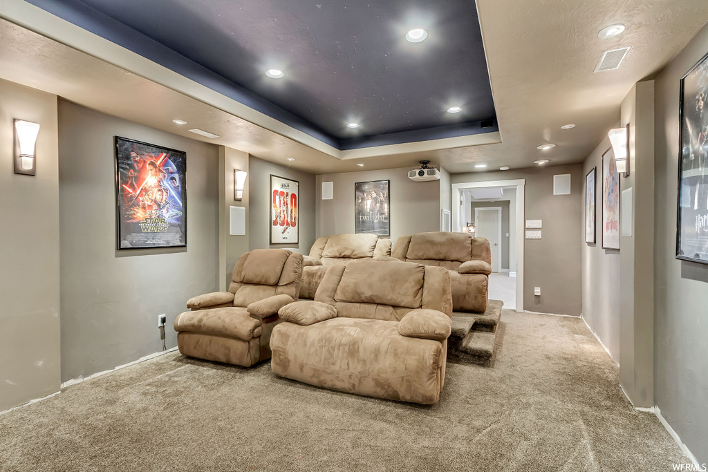 Home theater featuring light colored carpet and a raised ceiling