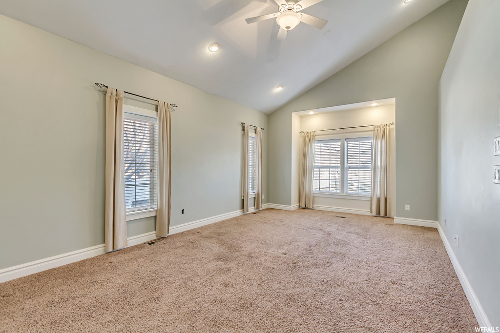 Carpeted spare room featuring ceiling fan and high vaulted ceiling