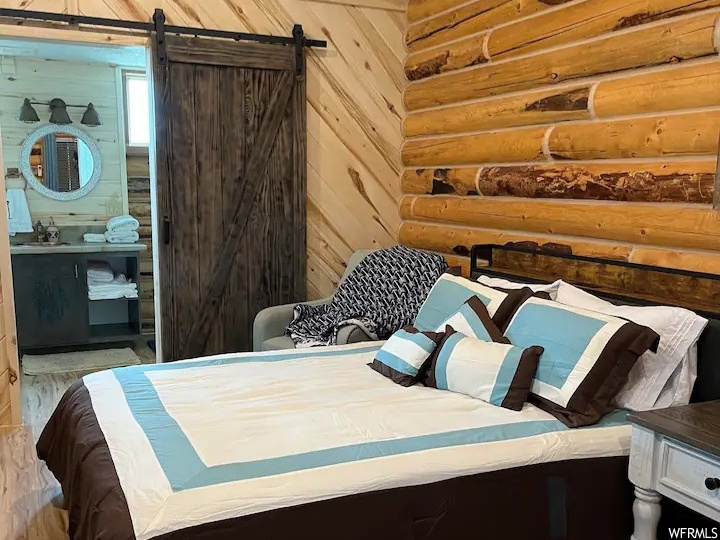 Bedroom with wood ceiling, a barn door, wood walls, connected bathroom, and wood-type flooring