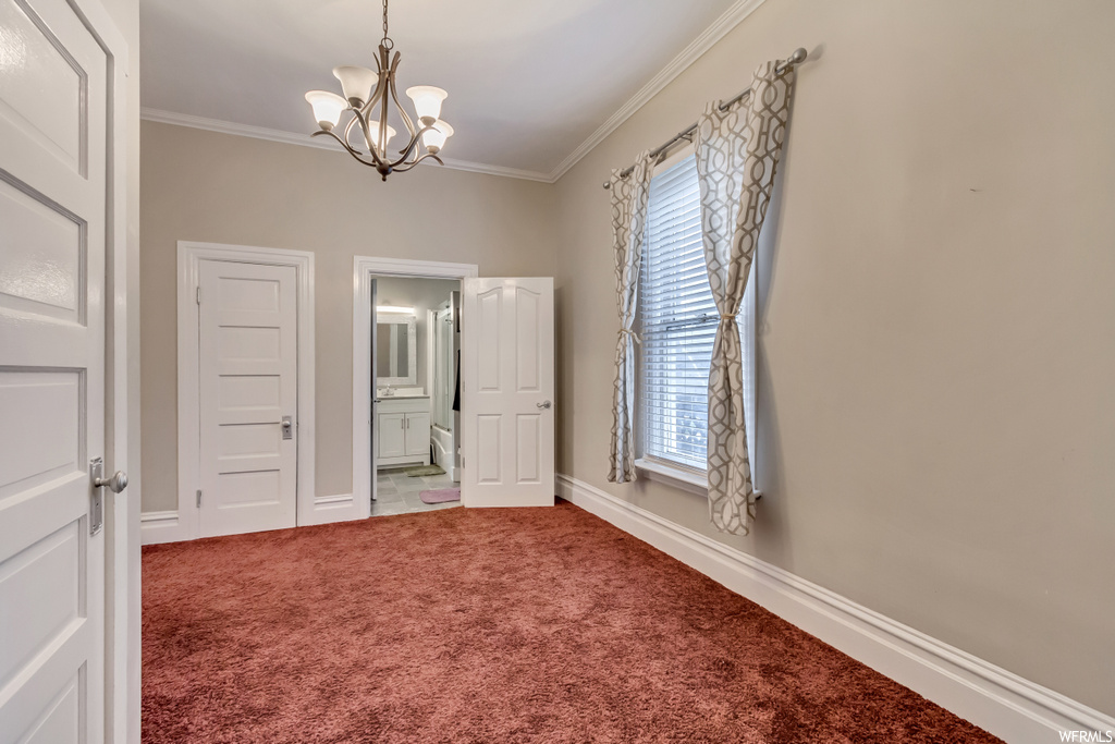 Spare room featuring ornamental molding, a notable chandelier, and light carpet