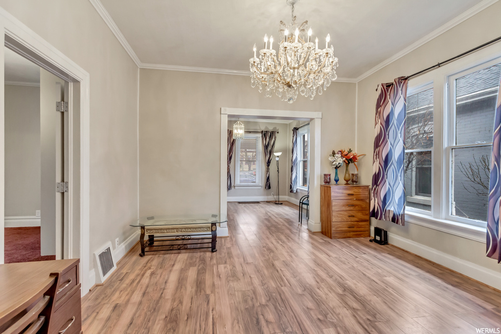 Interior space with a notable chandelier, light hardwood / wood-style floors, plenty of natural light, and crown molding