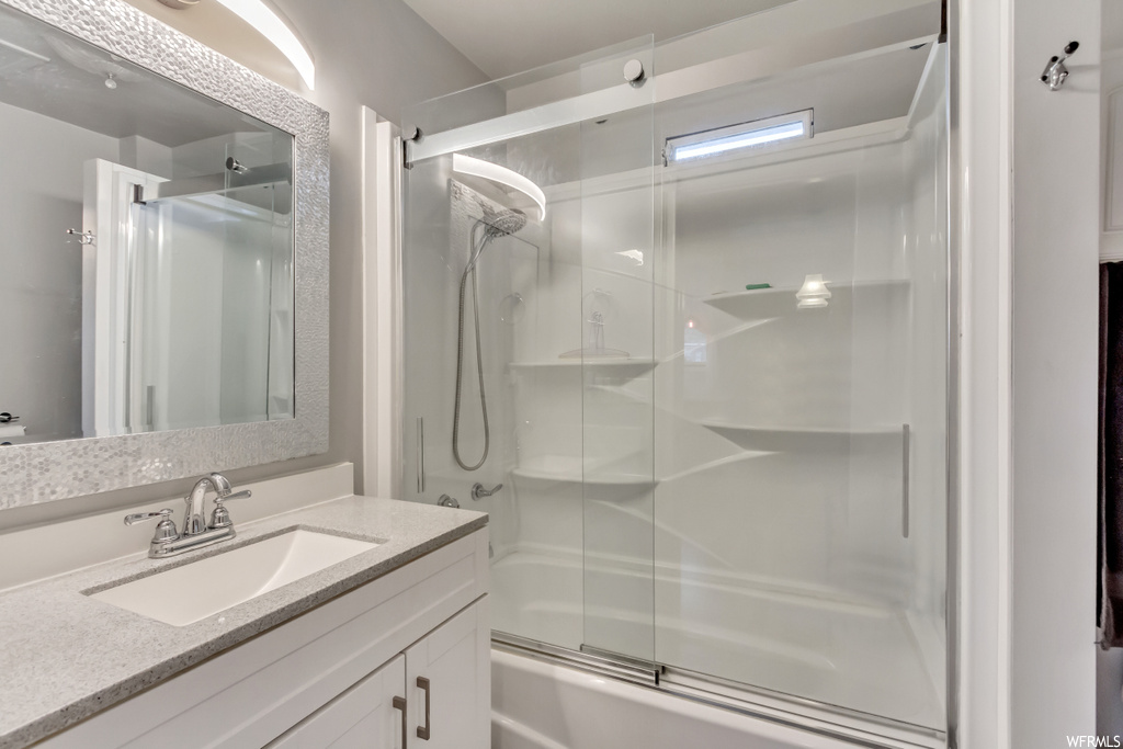 Bathroom with enclosed tub / shower combo and vanity with extensive cabinet space