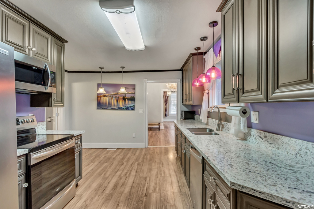 Kitchen featuring sink, hanging light fixtures, stainless steel appliances, and light hardwood / wood-style floors