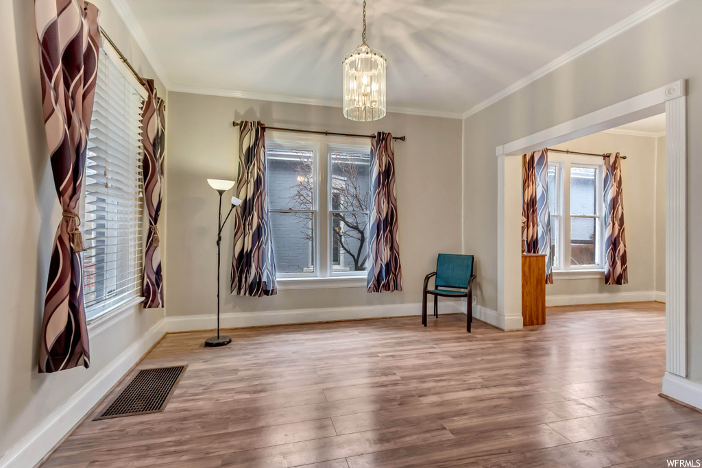 Interior space featuring a notable chandelier, crown molding, and light hardwood / wood-style floors