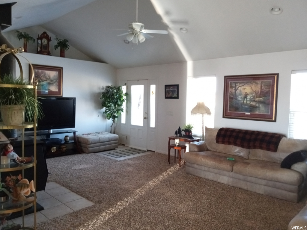 Carpeted living room featuring ceiling fan, a healthy amount of sunlight, and vaulted ceiling