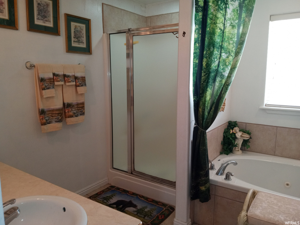 Bathroom featuring shower with separate bathtub and sink