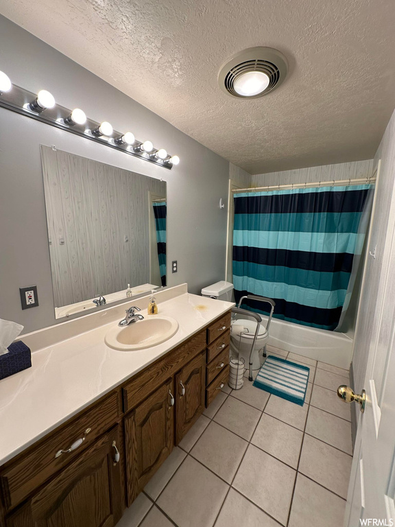 Full bathroom featuring toilet, a textured ceiling, tile floors, and oversized vanity
