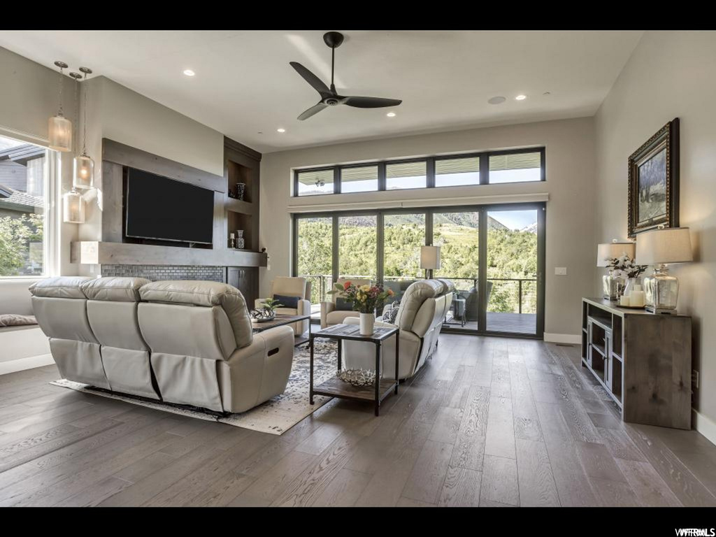 Living room with ceiling fan, plenty of natural light, and dark hardwood / wood-style flooring