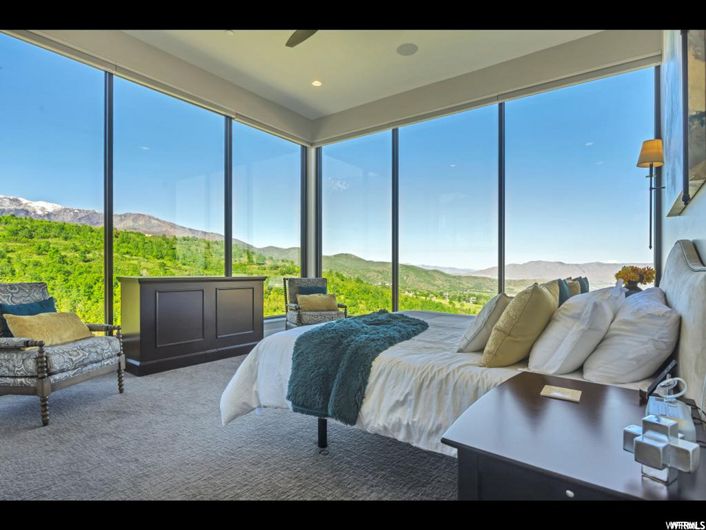 Bedroom with ceiling fan, carpet floors, multiple windows, and a mountain view