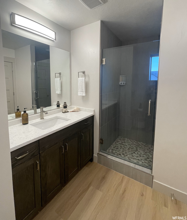 Bathroom with an enclosed shower, hardwood / wood-style flooring, and vanity
