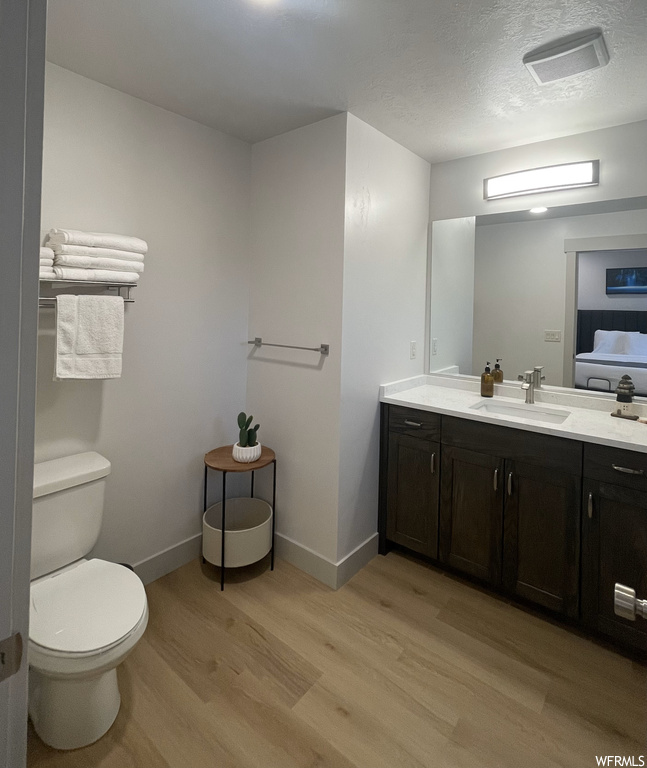 Bathroom featuring toilet, vanity, a textured ceiling, and hardwood / wood-style floors