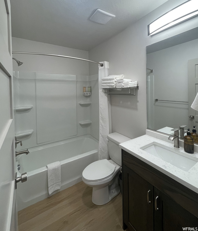 Full bathroom with toilet, vanity, shower / tub combo with curtain, and wood-type flooring