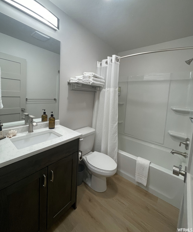 Full bathroom featuring vanity, shower / bath combo with shower curtain, toilet, and hardwood / wood-style flooring