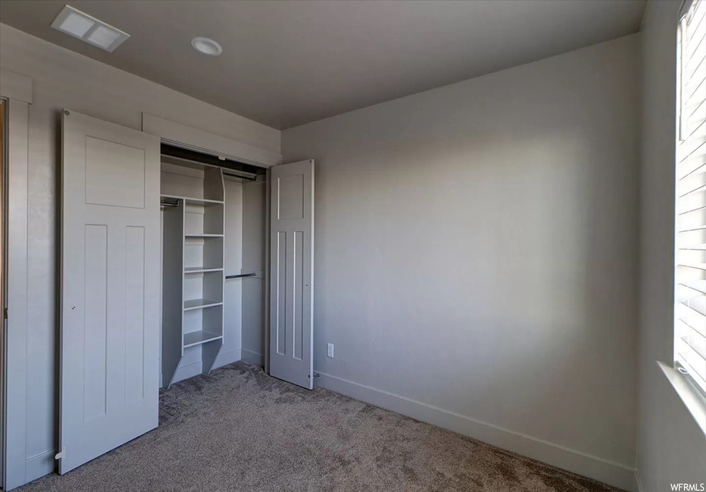 Unfurnished bedroom with multiple windows, a closet, and dark colored carpet