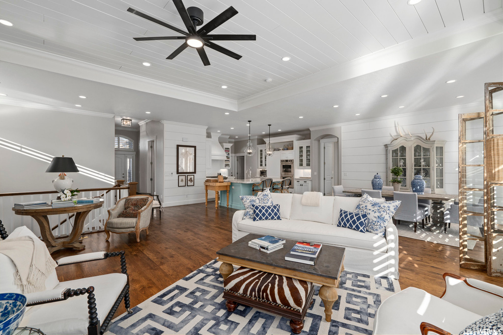 Living room featuring ceiling fan, a raised ceiling, dark hardwood / wood-style flooring, and crown molding