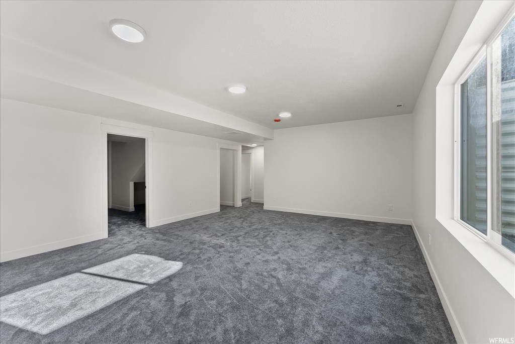 Empty room featuring plenty of natural light and dark colored carpet