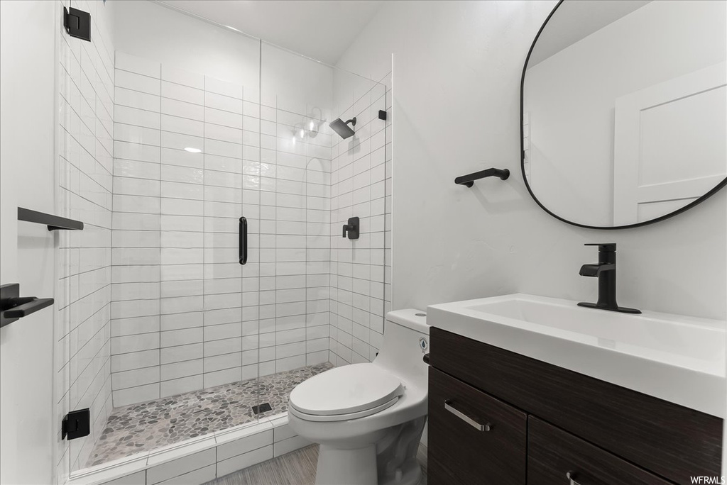 Bathroom featuring toilet, a shower with door, and oversized vanity