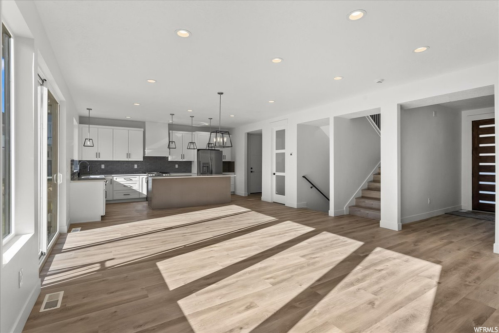 Kitchen with a center island, white cabinetry, light hardwood / wood-style floors, and backsplash