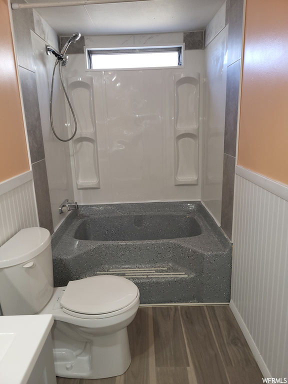 Full bathroom with toilet, vanity, plenty of natural light, and hardwood / wood-style floors