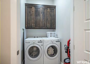 Clothes washing area with cabinets and separate washer and dryer
