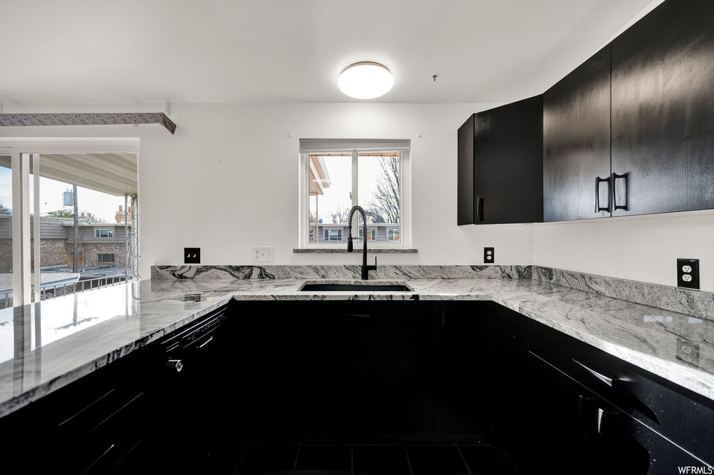 Kitchen featuring light stone countertops, a wealth of natural light, and sink