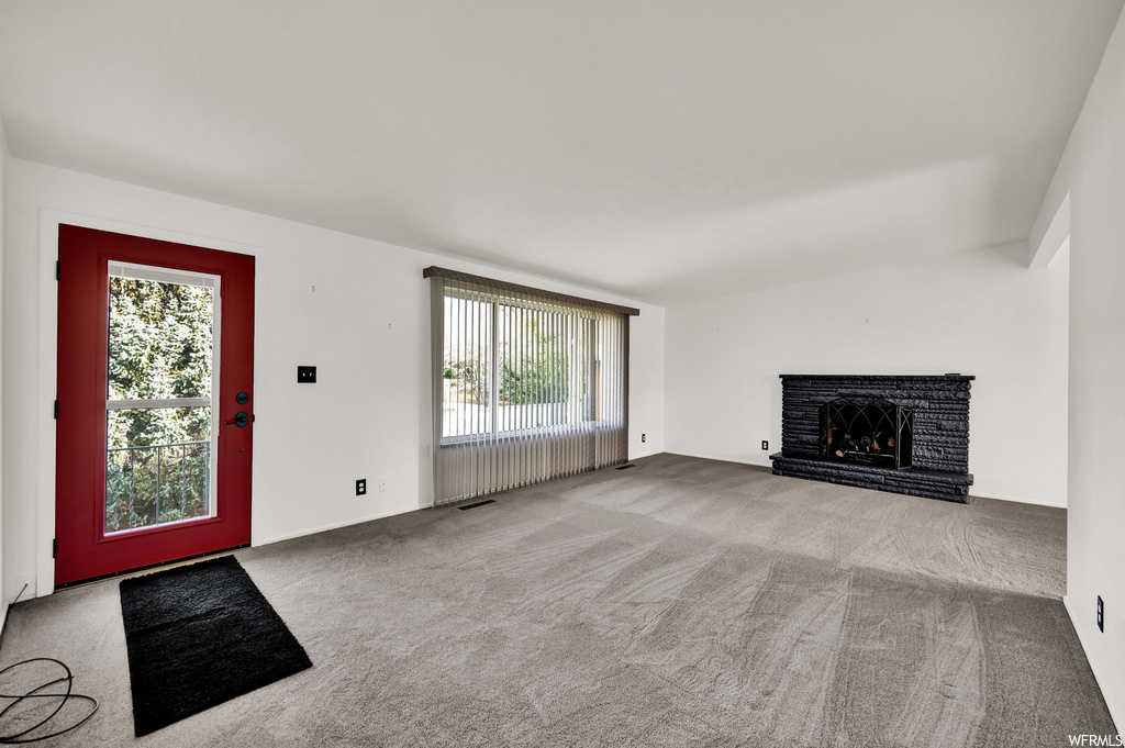 Carpeted foyer entrance featuring a brick fireplace and a wealth of natural light