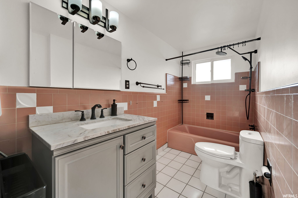 Full bathroom featuring toilet, tile floors, tile walls, and tiled shower / bath