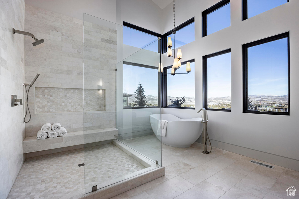 Bathroom featuring tile floors, shower with separate bathtub, and a chandelier