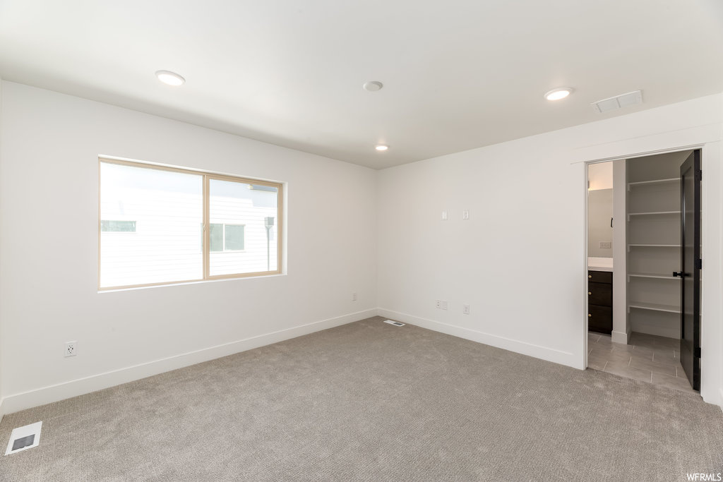 Unfurnished bedroom featuring a closet, light colored carpet, and a walk in closet