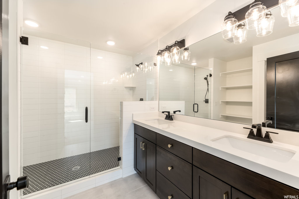 Bathroom featuring dual sinks, an enclosed shower, a chandelier, oversized vanity, and tile floors