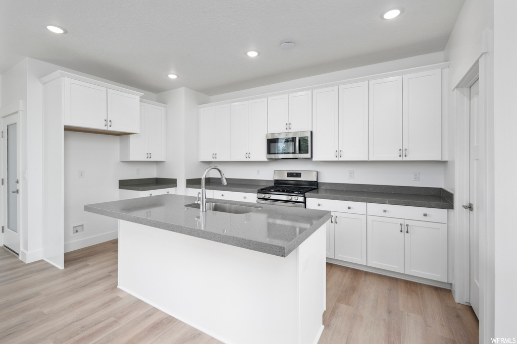 Kitchen featuring white cabinets, sink, appliances with stainless steel finishes, and light hardwood / wood-style floors