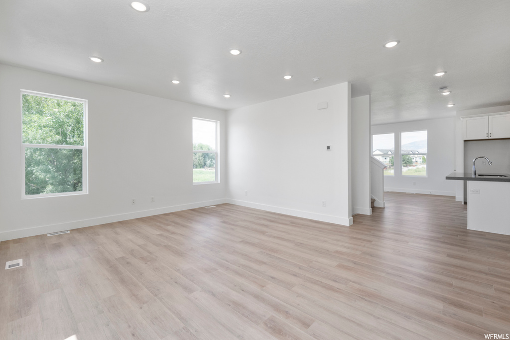 Unfurnished living room with a wealth of natural light, sink, and light hardwood / wood-style floors