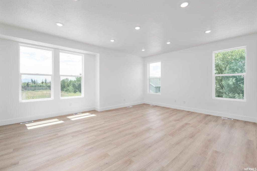 Empty room featuring light wood-type flooring and a healthy amount of sunlight