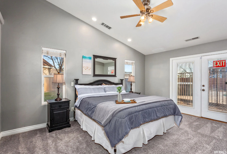 Bedroom with dark carpet, multiple windows, ceiling fan, and access to exterior
